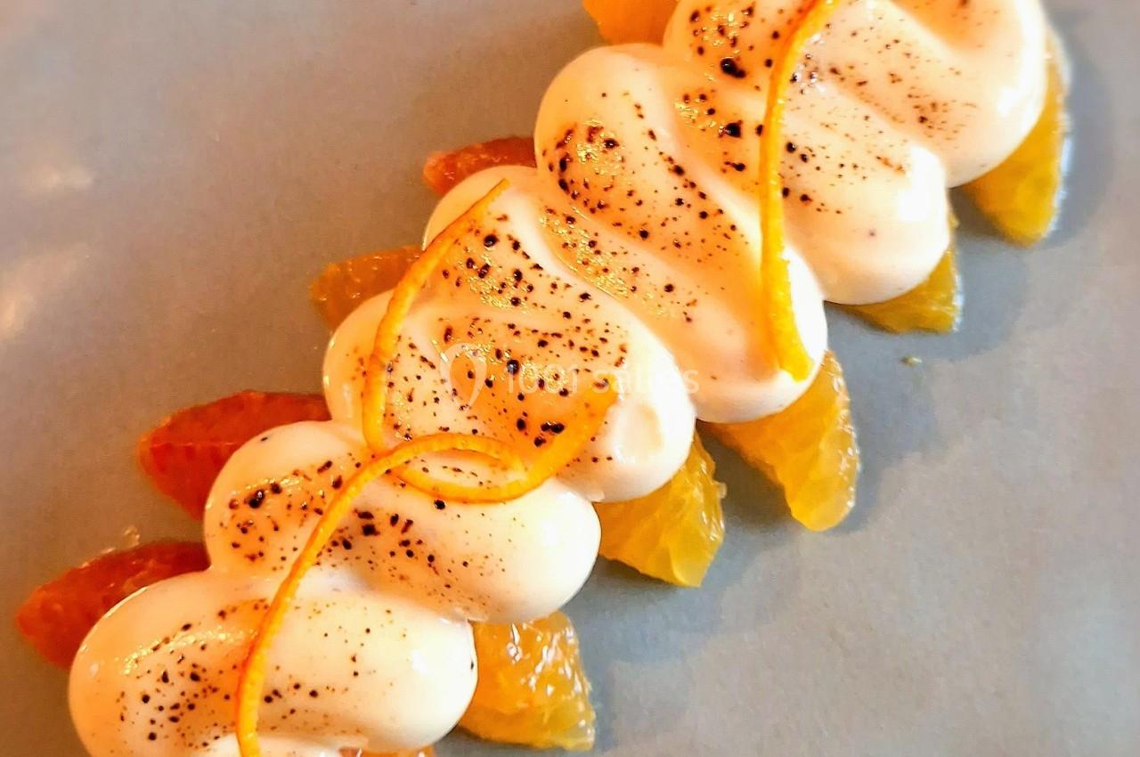 Dessert composé de segments d'agrumes et de crème légèrement caramélisée, décoré de zestes d'orange.