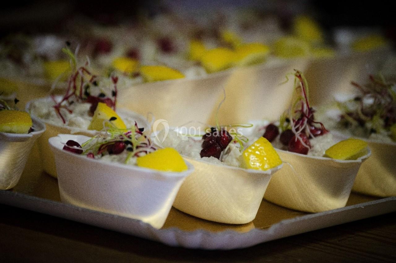 Coupes individuelles garnies de mousse blanche, morceaux de mangue, graines rouges et pousses décoratives.