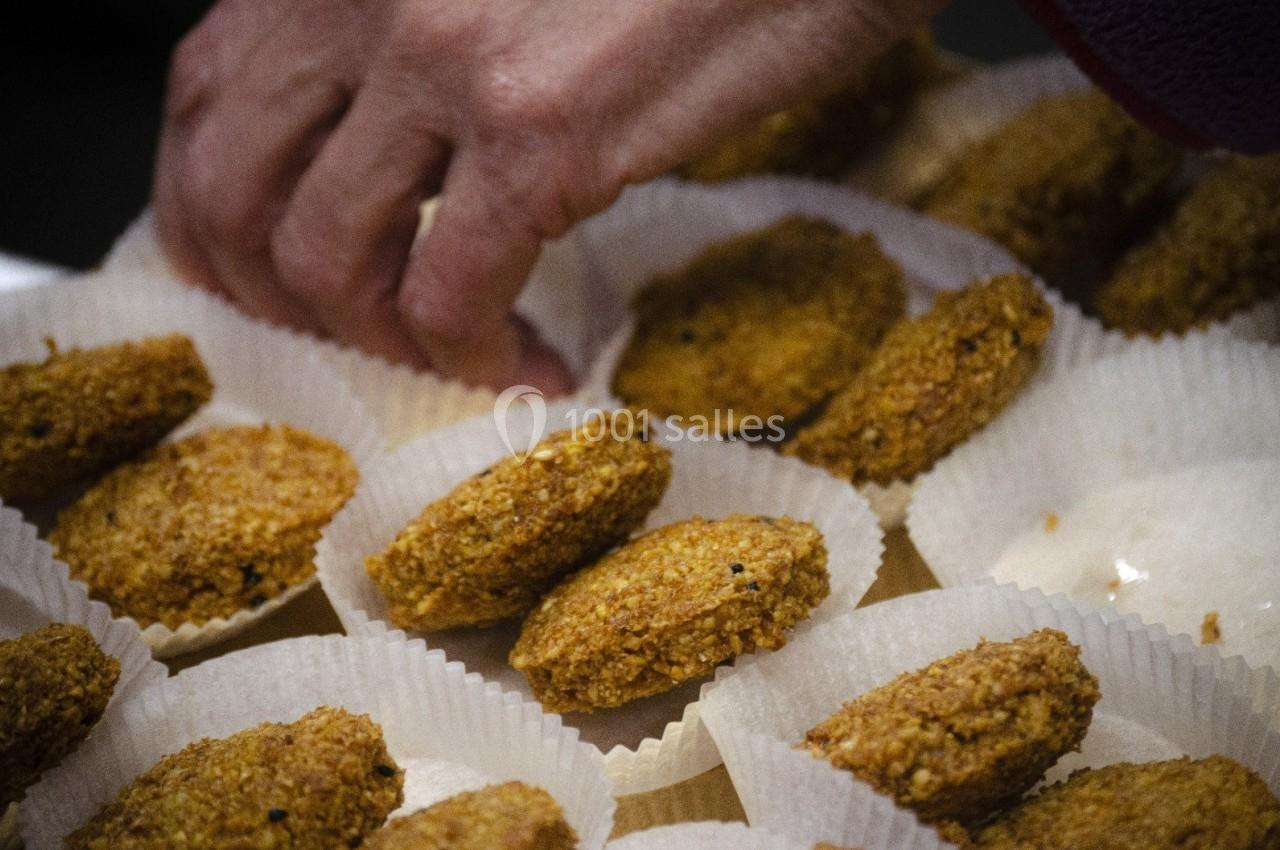 Main disposant des galettes dorées dans des caissettes en papier blanc.