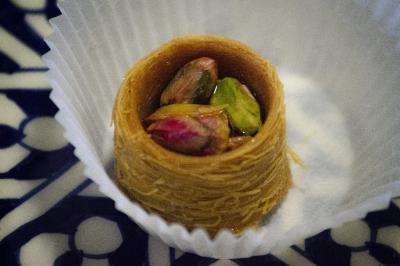 Assiette garnie de falafels dorés entourés de feuilles de salade et accompagnée de pinces en métal.