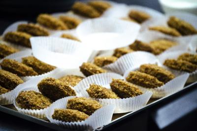 Assiette garnie de falafels dorés entourés de feuilles de salade et accompagnée de pinces en métal.