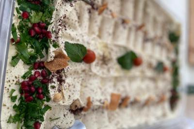 Assiette garnie de falafels dorés entourés de feuilles de salade et accompagnée de pinces en métal.