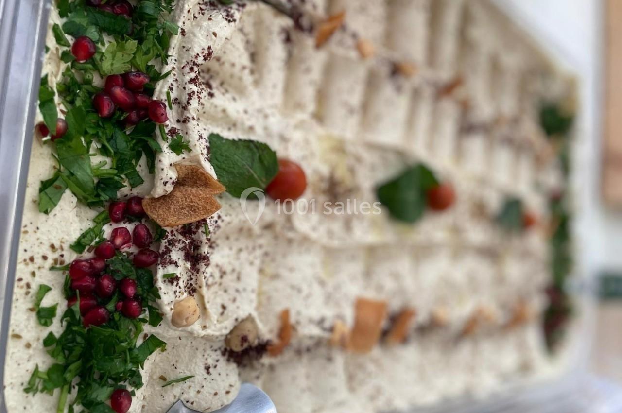 Plateau de houmous garni de persil, grenade, tomates cerises, feuilles de menthe et morceaux de pain pita.