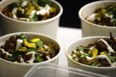 Assiette garnie de falafels dorés entourés de feuilles de salade et accompagnée de pinces en métal.