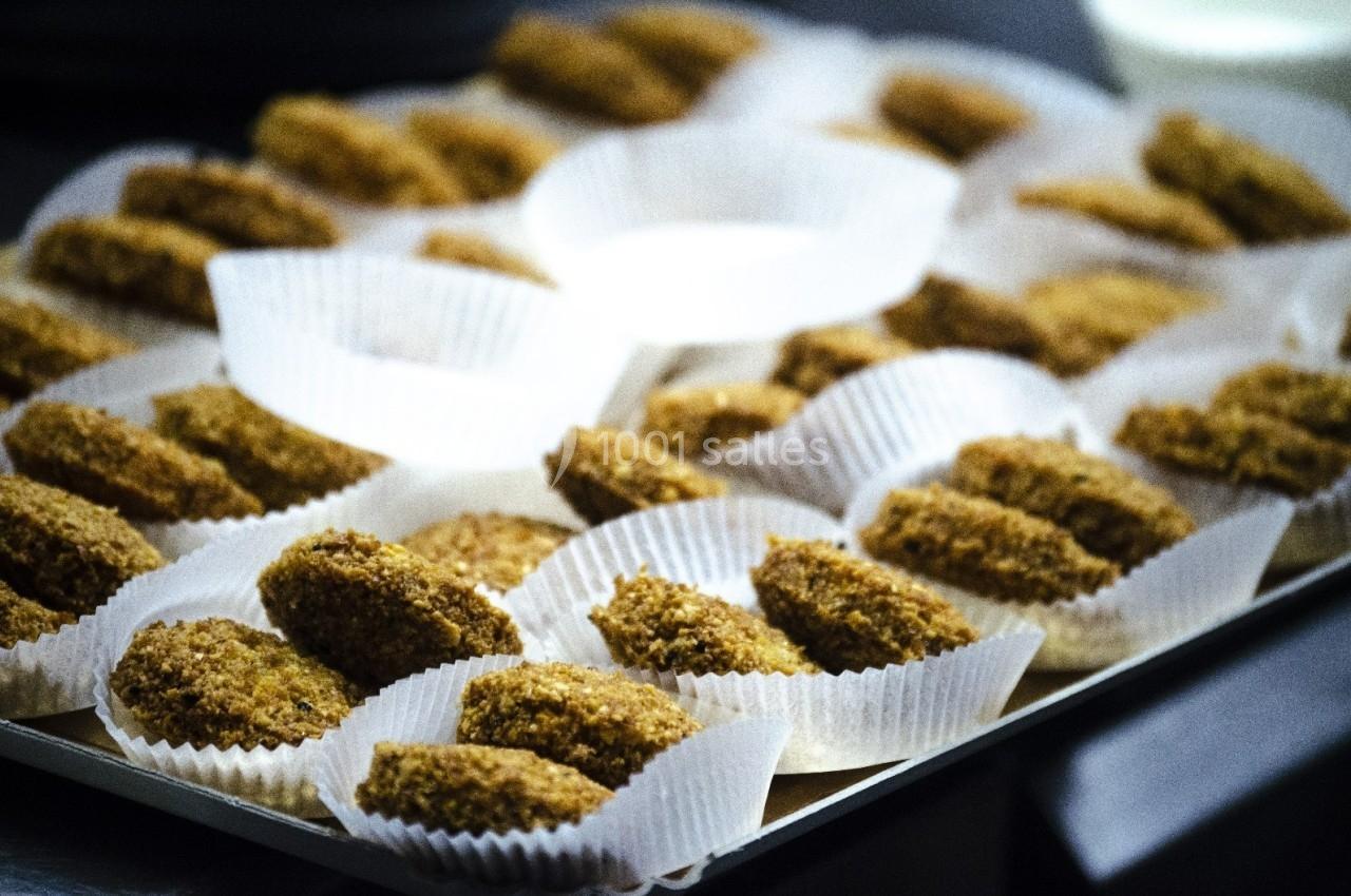Assortiment de falafels disposés dans des caissettes en papier sur un plateau.