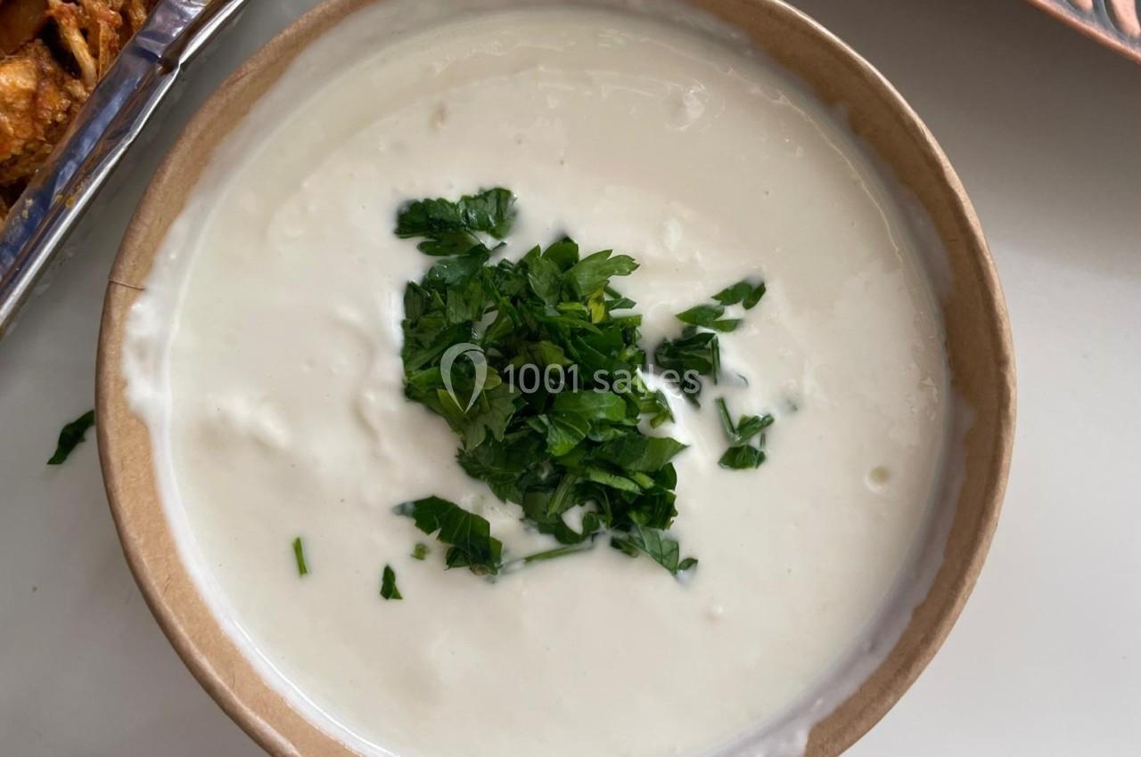 Bol de sauce blanche crémeuse garnie de feuilles de persil frais hachées.