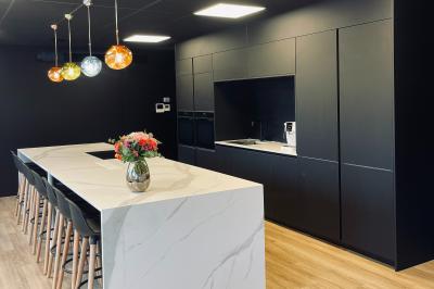 Miniature Location salle Lampertheim (Bas-Rhin) - Le 13 #9 Plante verte en pot noir avec des galets blancs, placée près d'un escalier en bois dans un espace intérieur lumineux.