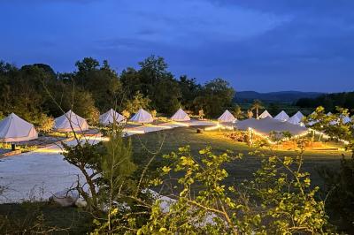 Fête nocturne en plein air avec un bar central, des invités debout et des lumières colorées sous une tente éclairée.