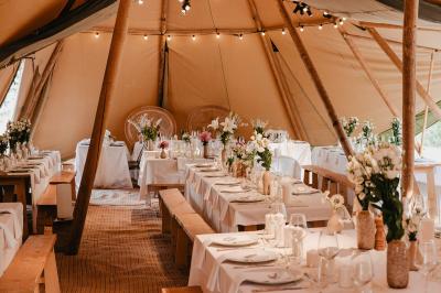 Fête nocturne en plein air avec un bar central, des invités debout et des lumières colorées sous une tente éclairée.