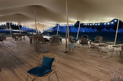 Fête nocturne en plein air avec un bar central, des invités debout et des lumières colorées sous une tente éclairée.