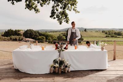 Fête nocturne en plein air avec un bar central, des invités debout et des lumières colorées sous une tente éclairée.