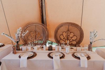 Fête nocturne en plein air avec un bar central, des invités debout et des lumières colorées sous une tente éclairée.