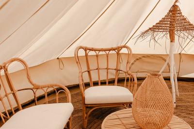 Fête nocturne en plein air avec un bar central, des invités debout et des lumières colorées sous une tente éclairée.