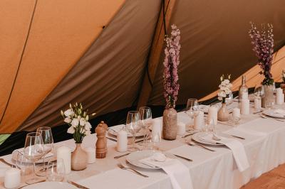 Fête nocturne en plein air avec un bar central, des invités debout et des lumières colorées sous une tente éclairée.