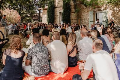 Fête nocturne en plein air avec un bar central, des invités debout et des lumières colorées sous une tente éclairée.