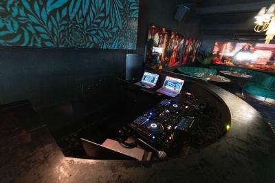 Enceinte noire fixée sur un poteau en bois, entourée de feuillage, sous un ciel bleu dégagé.