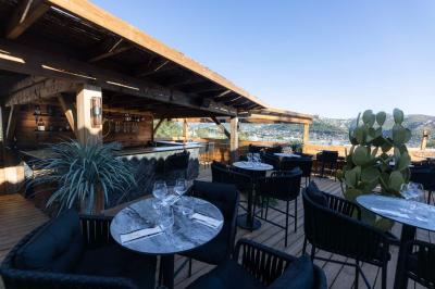 Enceinte noire fixée sur un poteau en bois, entourée de feuillage, sous un ciel bleu dégagé.