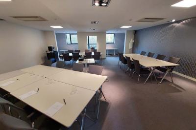 Quatre voitures sportives colorées alignées sur un parking en plein air, entourées de verdure.
