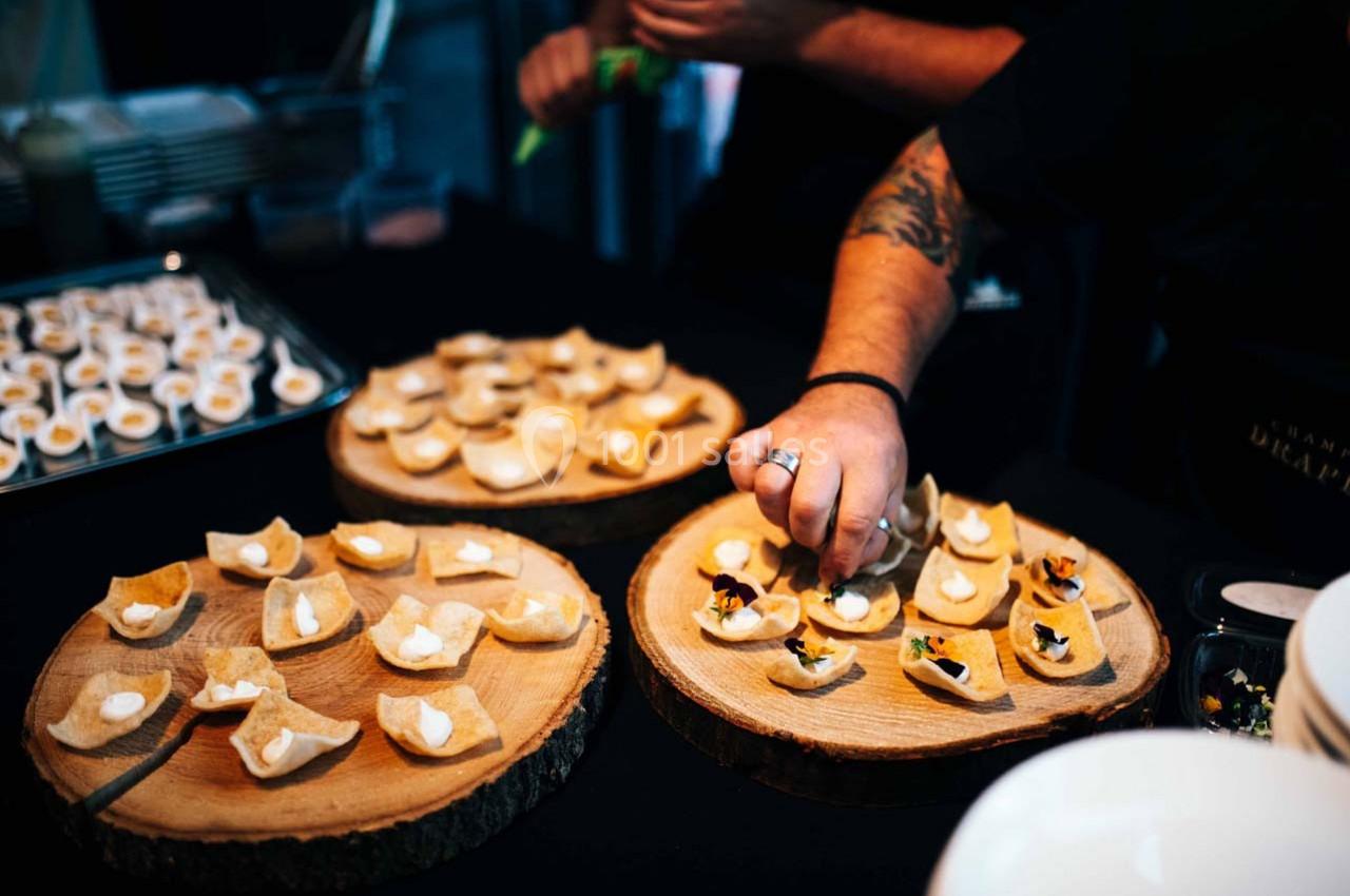 Des amuse-bouches sont disposés sur des plateaux en bois tandis qu'une personne ajoute des garnitures.