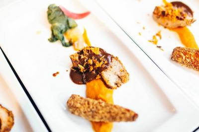 Quatre voitures sportives colorées alignées sur un parking en plein air, entourées de verdure.