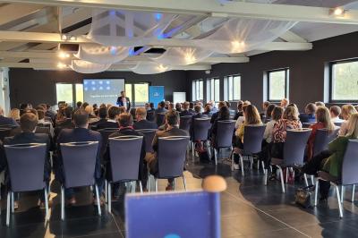 Quatre voitures sportives colorées alignées sur un parking en plein air, entourées de verdure.