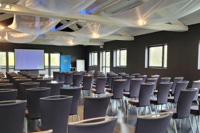 Quatre voitures sportives colorées alignées sur un parking en plein air, entourées de verdure.