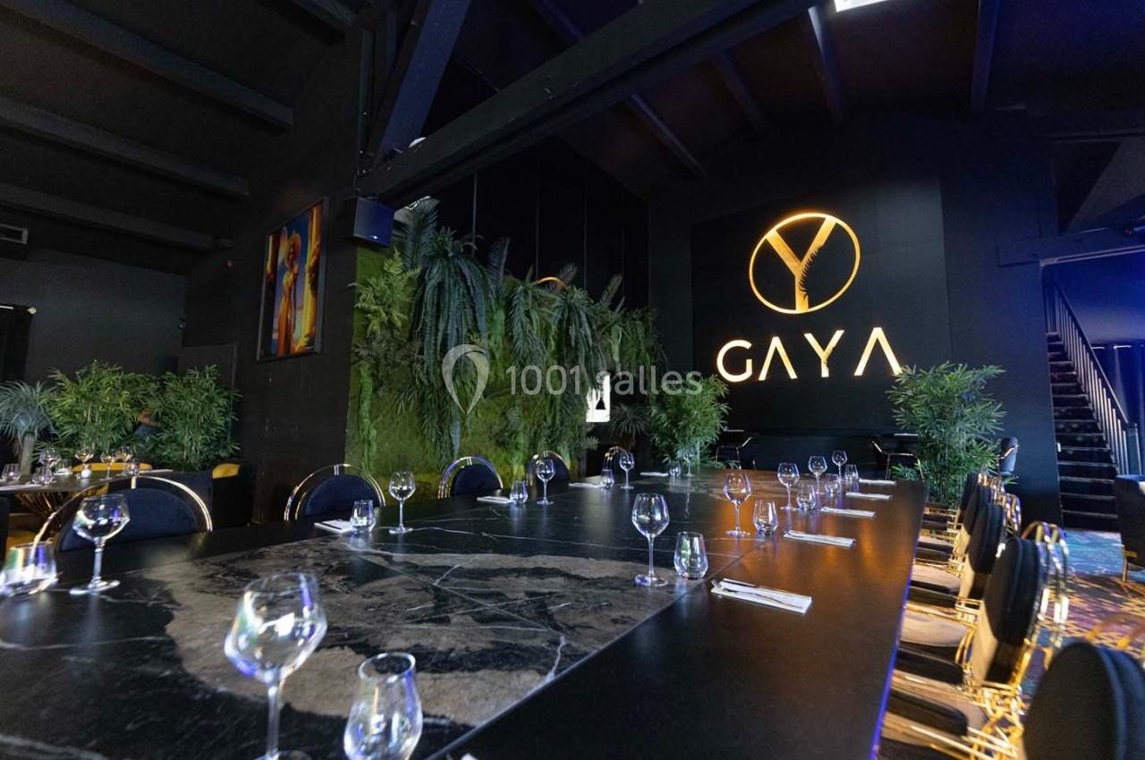 Salle de restaurant moderne avec une grande table en marbre noir, chaises élégantes et décoration végétale.