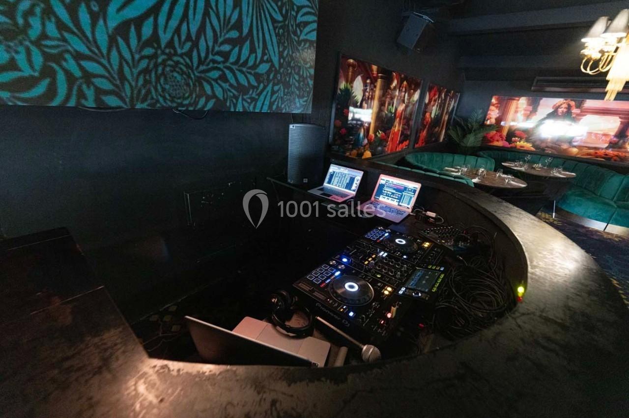 Poste de DJ avec platines, ordinateurs portables et câblage, dans un espace sombre décoré de motifs et lumières colorées.