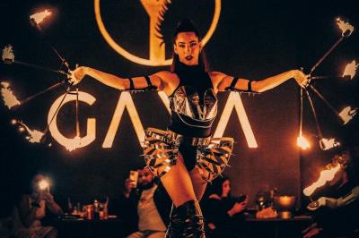 Artiste jonglant avec des torches enflammées dans une ambiance sombre, devant un logo lumineux en arrière-plan.