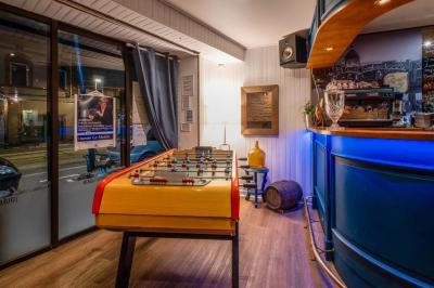 Salle avec un baby-foot, un mur en briques, un comptoir avec tabourets et une baie vitrée donnant sur la rue.