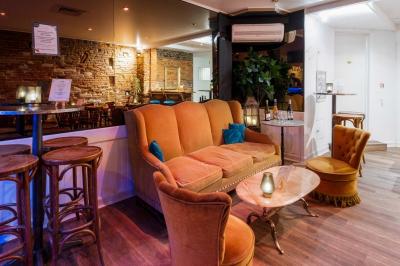 Salle avec un baby-foot, un mur en briques, un comptoir avec tabourets et une baie vitrée donnant sur la rue.