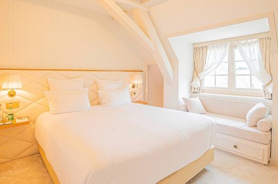 Salle de réception lumineuse avec tables décorées, chaises blanches et un grand lustre central sous une verrière.