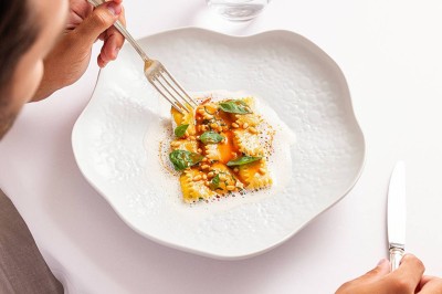 Salle de réception lumineuse avec tables décorées, chaises blanches et un grand lustre central sous une verrière.