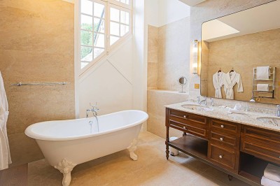 Salle de réception lumineuse avec tables décorées, chaises blanches et un grand lustre central sous une verrière.