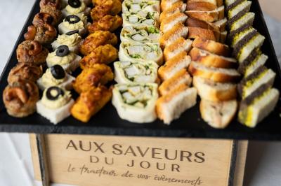 Table dressée avec des verres et un seau à champagne devant une baie vitrée, logo ’Aux Saveurs du Jour’ au mur.