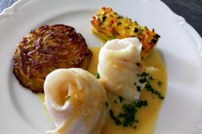 Table dressée avec des verres et un seau à champagne devant une baie vitrée, logo ’Aux Saveurs du Jour’ au mur.