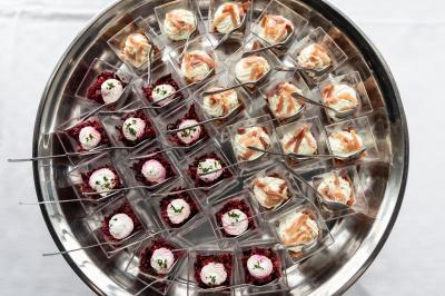 Plateau de verrines variées, comprenant des préparations à base de betterave et de saumon, disposées sur une table blanche.