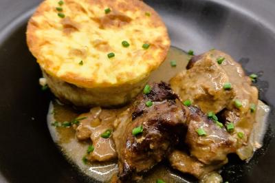 Table dressée avec des verres et un seau à champagne devant une baie vitrée, logo ’Aux Saveurs du Jour’ au mur.