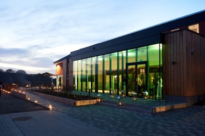 Lavabo moderne avec robinet chromé, serviettes blanches pliées et produits de toilette sur un plan en bois.