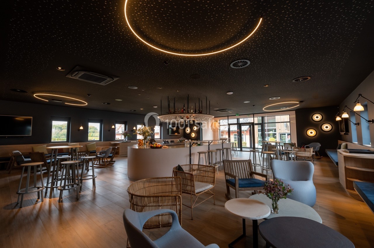 Salle moderne et élégante avec un éclairage tamisé, des meubles variés et un bar central lumineux.