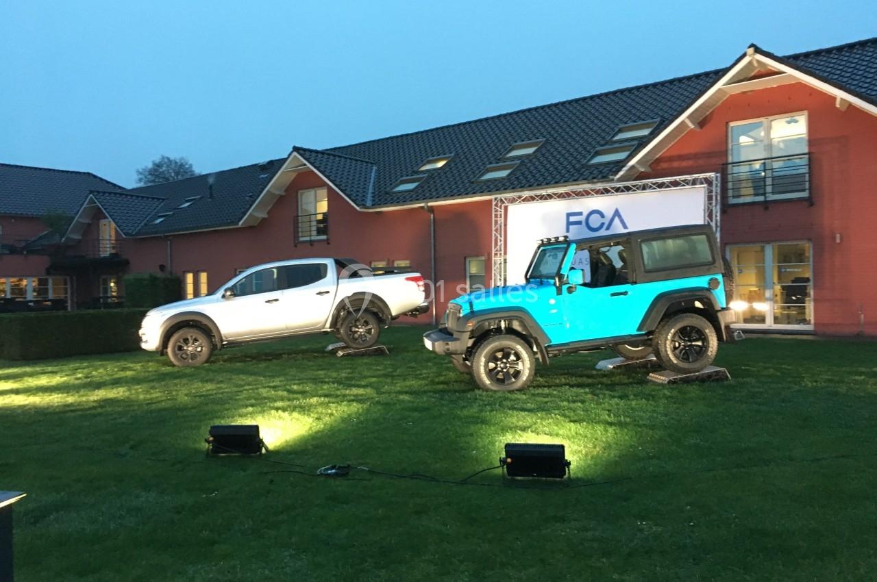 Deux véhicules tout-terrain exposés sur une pelouse devant un bâtiment, éclairés par des projecteurs.