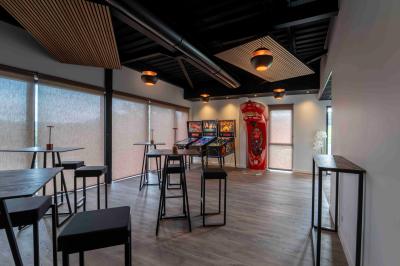 Cuisine moderne avec plancher en bois, tables hautes, chaises noires, réfrigérateur, micro-ondes et cafetière.