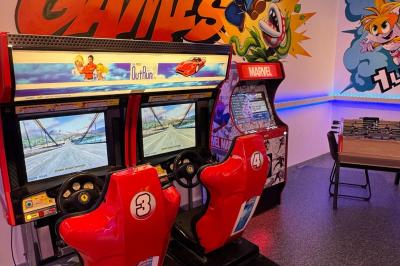 Cuisine moderne avec plancher en bois, tables hautes, chaises noires, réfrigérateur, micro-ondes et cafetière.