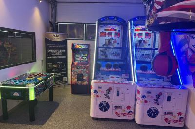 Cuisine moderne avec plancher en bois, tables hautes, chaises noires, réfrigérateur, micro-ondes et cafetière.