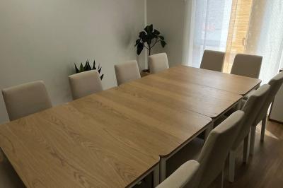 Cuisine moderne avec plancher en bois, tables hautes, chaises noires, réfrigérateur, micro-ondes et cafetière.