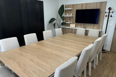 Cuisine moderne avec plancher en bois, tables hautes, chaises noires, réfrigérateur, micro-ondes et cafetière.