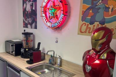 Cuisine extérieure moderne avec comptoir en bois, abri noir et lumière naturelle filtrée par le soleil.