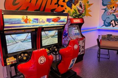 Cuisine extérieure moderne avec comptoir en bois, abri noir et lumière naturelle filtrée par le soleil.