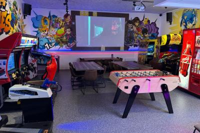 Cuisine extérieure moderne avec comptoir en bois, abri noir et lumière naturelle filtrée par le soleil.