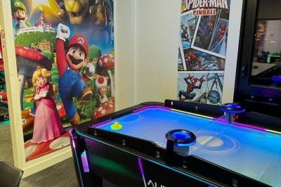 Cuisine extérieure moderne avec comptoir en bois, abri noir et lumière naturelle filtrée par le soleil.